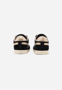 Sneakers neri in suede con accenti dorati, forma arrotondata e suola in gomma beige. Presentano un colletto in pelle liscia e strisce a contrasto.
