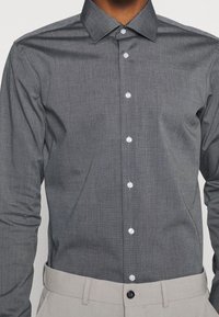 Grijze langärmige knopsluiting shirt met een textuurstof, spitse kraag en lichte knopen, gecombineerd met een lichtgekleurde tailleband.