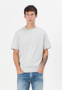 Grey short-sleeved t-shirt with a crew neck, made of cotton. Features a small brand logo on the shoulder and a relaxed fit.