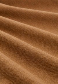 Brauner Stoff mit einer glatten, strukturierten Oberfläche, der wellige Falten aufweist, die seine weiche, taktile Qualität betonen. Konsistente Farbe im gesamten Stoff.