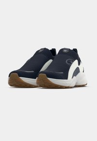 Σκούρα μπλε αθλητικά παπούτσια από δίχτυ με λευκές λεπτομέρειες, στρογγυλερή μύτη, ελαστικό κολάρο και υφασμένο πέλμα. Διαθέτουν λεπτομέρεια με λογότυπο στο πλάι.