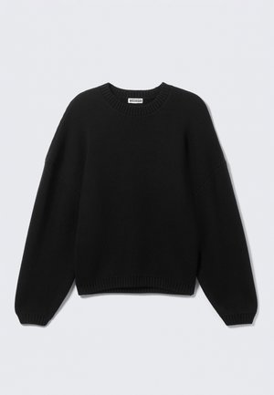 Melns adīts džemperis ar apaļu izgriezumu un plašām, balona tipa piedurknēm. Ribota apakša un aproces piešķir vienkāršajam dizainam struktūru.