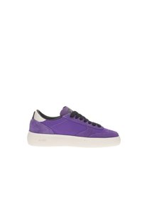 Zapatilla púrpura con material de gamuza y malla, cordones negros, suela blanca texturizada y acentos plateados en el talón. Diseño de punta redondeada.