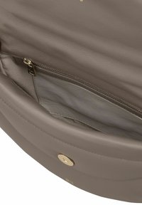 Interieur van een taupe lederen handtas met een ritsvak en een magneetsluiting, voorzien van nette stikdetails.