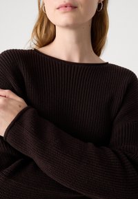 Maglione a maglia marrone con una scollatura ampia e maniche lunghe, che presenta un motivo a coste e un tessuto morbido e accogliente.