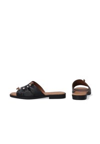 Sandales en cuir noir à enfiler avec trois bandes décoratives et une semelle plate. L'intérieur présente une doublure brun clair avec une texture subtile.