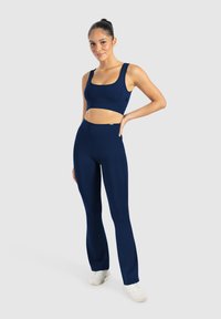 Completo sportivo blu navy composto da un top corto con spalline larghe e leggings a vita alta svasati, realizzati in tessuto elasticizzato e morbido.