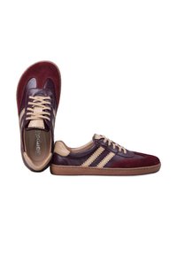 Paire de baskets en cuir bordeaux et beige avec lacets, une chaussure debout et l'autre couchée sur le côté sur fond blanc.