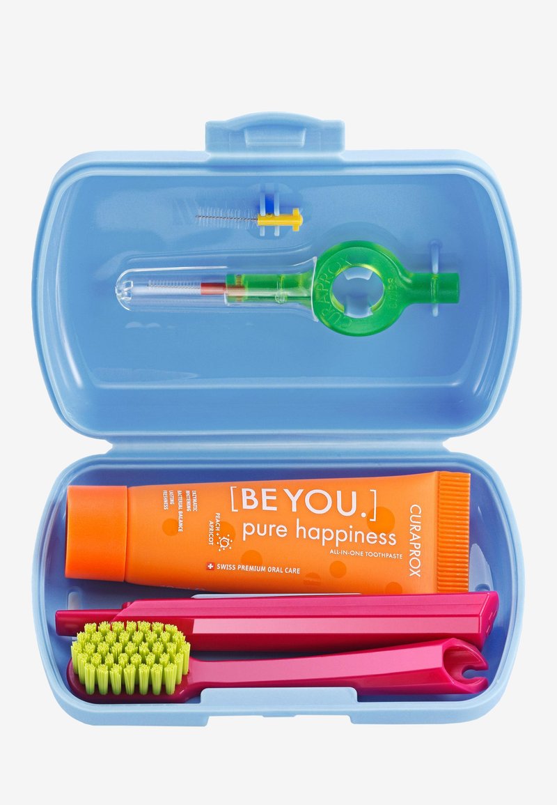 Boîte rectangulaire bleue contenant une brosse à dents rose, un outil dentaire rose, un accessoire vert et un dentifrice orange étiqueté « [SOIS TOI.] pure bonheur. »