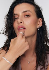 Srebrny zestaw biżuterii, składający się z pierścionka, bransoletki, kolczyków i naszyjnika. Wyróżnia się iskrzącymi się kamieniami oraz delikatnymi wzorami o błyszczącym wykończeniu.