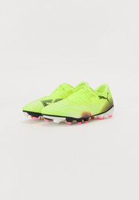 Bright neon yellow soccer cleats with black and pink accents, textured surface, lace-up design, and a lightweight construction.