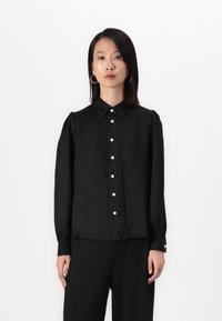 Black long-sleeve blouse with a collared neckline, pleated texture, and button closure featuring decorative pearl-like buttons.