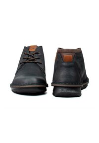 Zapatos de cuero negro con punta redondeada, detalles en marrón y tacón texturizado, con diseño de cordones y suela flexible de goma.