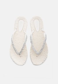 Infradito bianchi in gomma con suole texturizzate e una cinghia luccicante decorata con cristalli trasparenti, che mostrano un design semplice ed elegante.