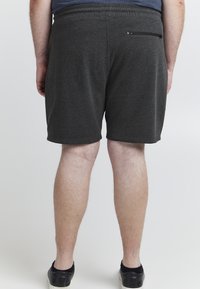 Tamno sive kratke hlače napravljene od mekog materijala, s zatvaračem na stražnjem džepu i elastičnom waistband-om, s ravnim krojem na otvorima nogavica.