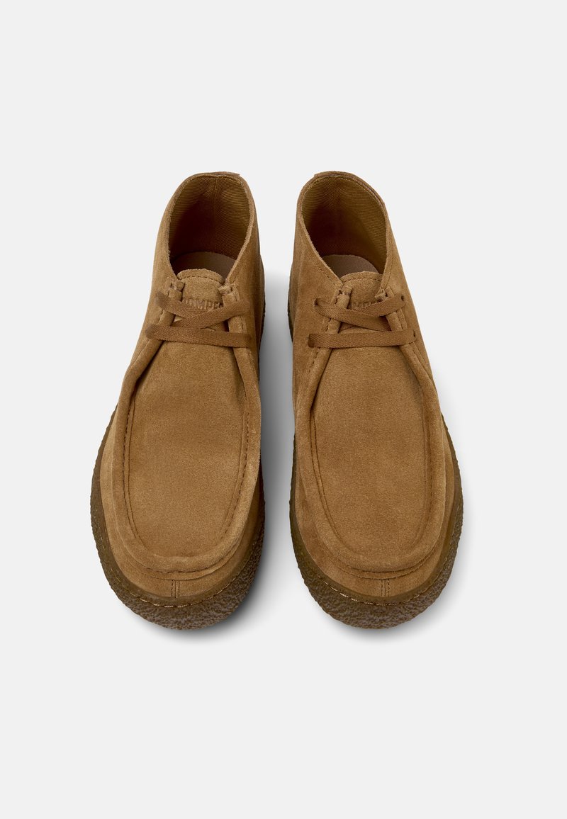 Brown suede ankle boots with rounded toe, flat laces, and textured rubber sole. Minimalist design with clean lines and simple construction.