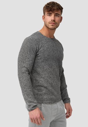 Gray long-sleeve sweater with a textured knit pattern. Crew neckline and fitted design, paired with light-colored pants.