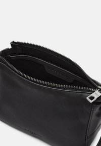 Pochette in pelle nera con chiusura a zip, caratterizzata da una texture morbida e un design semplice. L'interno presenta un'etichetta del marchio e una fodera liscia.