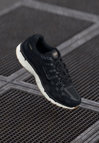 Černé tenisky Nike P-6000 s texturovaným síťovaným svrškem, s tkaničkovým zapínáním a bílou mezipodešví. Disponují gumovou podešví s hnědými akcenty.