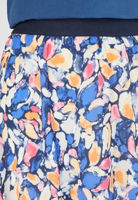 Tejido con un patrón floral en colores azul, rosa, naranja y crema; presenta una textura suave y una cinturilla elástica.