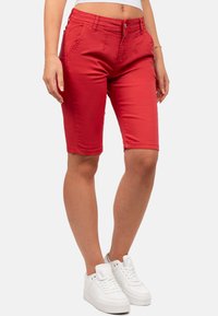 Rode denim bermuda shorts met een aansluitend design, voorzakken en riemlussen, gecombineerd met witte sneakers. Soepele textuur.
