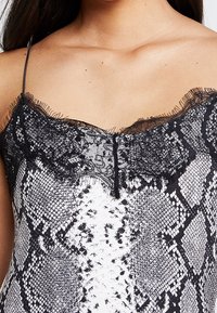 Camisole med ett svart och vitt ormprint, med en delikat spetskant längs halsringningen och en smal spagettistil.