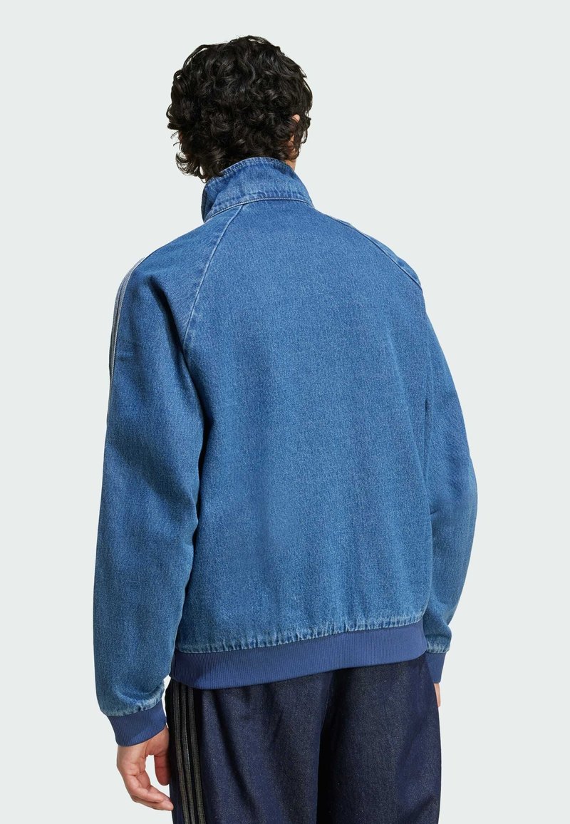 Denimjakke i medium blå med høj krave, ribbede manchetter og talje, med en afslappet pasform og raglanærmer, struktureret overflade.