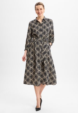 Langärmliges, knöpfbares Kleid mit einem schwarzen Blumenmuster auf beigem Hintergrund. Taillierter Schnitt, fließender Rock und seitliche Taschen vorhanden.