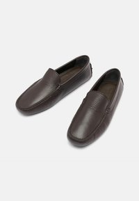Smeđe kožne loaferice s teksturiranom površinom, dizajnom za jednostavno obuvanje, zaobljenim vrhom i minimalnim šavovima na gornjem dijelu i potplatu.