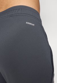 Mørkegrå sportsshorts med en glat tekstur, elastisk talje og et hvidt "AEROREADY" logo på siden.