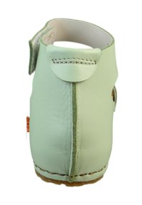 Zapato de cuero verde claro con tacón curvado, detalles de costura y una correa ajustable. Textura suave y un botón decorativo en el lateral.