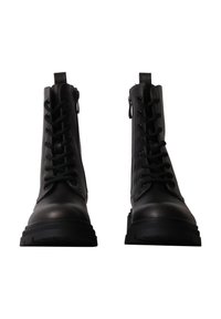 Paire de bottes de combat en cuir noir à lacets, avec semelles épaisses et fermetures éclair latérales, vues de face sur fond blanc.