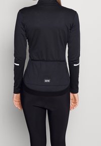 Black long-sleeve jacket with a high collar, elastic hem, reflective accents on the sleeves, and a GORE logo on the back.