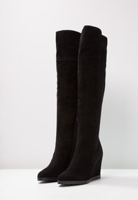 Zwarte suède over-the-knee laarzen met een sleehak, voorzien van een zijrits en een gladde textuur. Strakke lijnen en een aansluitend ontwerp.