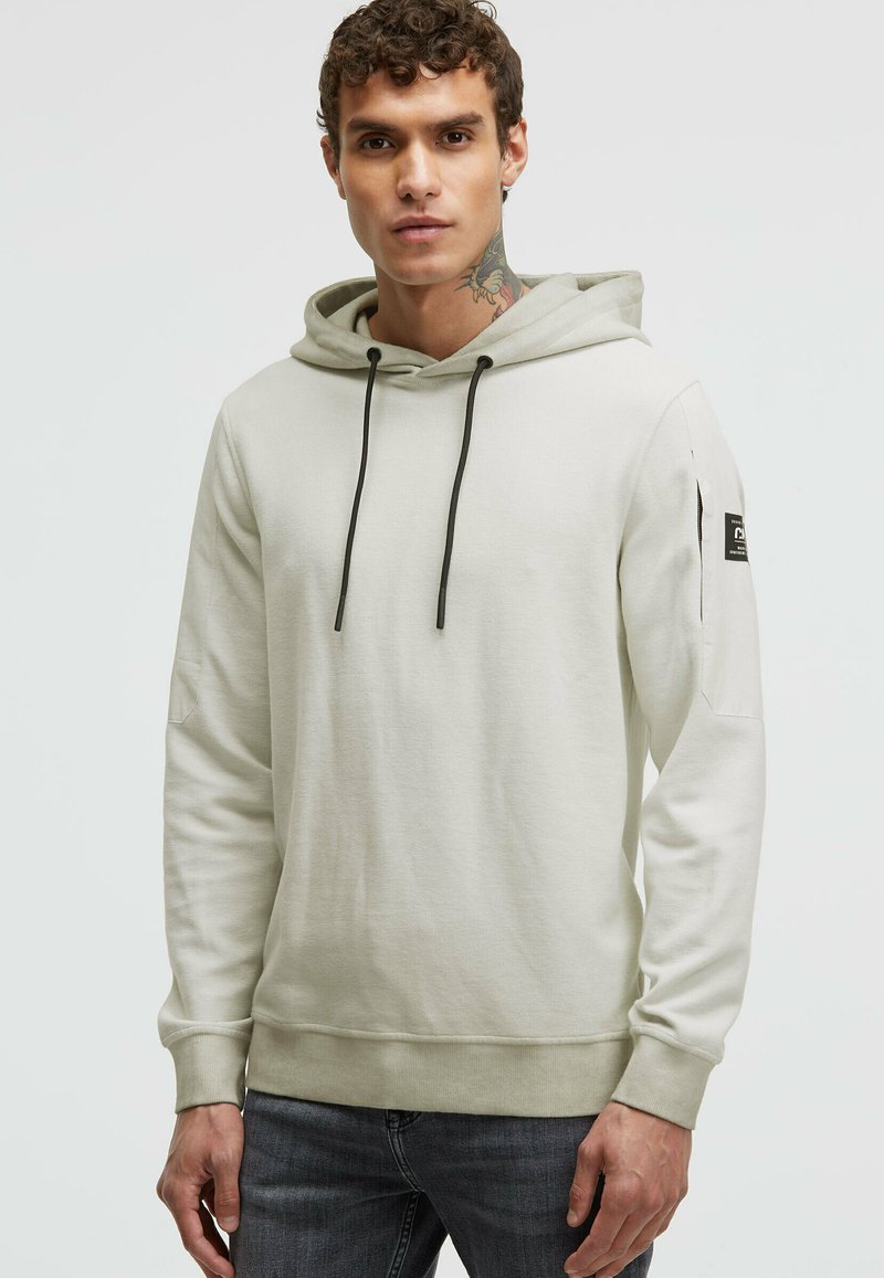 Light gray hoodie with a kangaroo pocket, black drawstrings, and a patch on the left sleeve. Soft texture and fitted design.