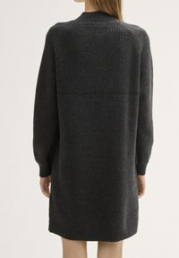 Gebreid grijs jurkje met een ronde halslijn, geribbelde textuur op het bovenste deel en aansluitende mouwen. De lengte reikt tot halverwege de bovenbenen. Zacht materiaal.