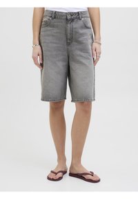 Harmaat farkkushortsit, joissa on suora leikkaus, normaali vyötärö ja etutaskut, käytettynä purppuranväristen flip-floppien kanssa.