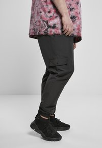 Mustikka cargo housut slim fit -mallilla ja napilla varustetulla sivutaskulla. Yhdistettynä mustiin korkeatoppaisiin kenkiin, joissa on nauhat ja teksturoitu muotoilu.