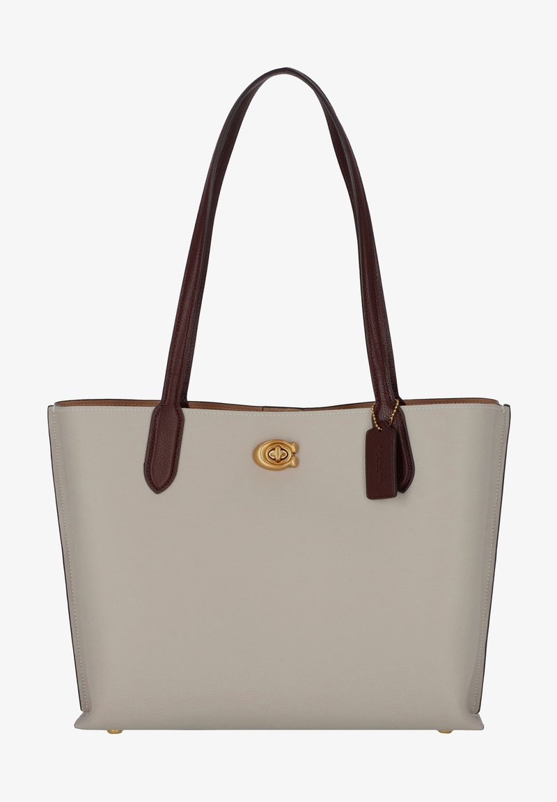 Tote taske i beige læder med glat overflade, der har mørkebrune håndtag, guldlogo og et lille matchende mærke.