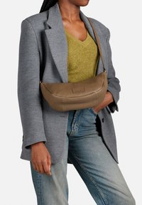 Borsa a tracolla in pelle marrone con forma curva e finitura testurizzata. Presenta una tracolla corta e un logo goffrato discreto.