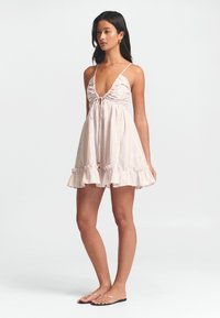 Robe à bretelles en tissu léger avec des rayures subtiles, décolleté en V profond, corsage froncé, nouée à l'avant, ourlet à volants et coupe décontractée.