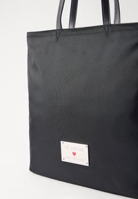 Black textured tote bag with two sleek handles and a metallic logo plaque reading "LOVE MOSCHINO" and "Made with love."