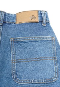 Jeans i denim med en ljusblå nyans, prydda med en rektangulär label i tanfärgad läder vid midjan och en enda bakficka, sydd med kontrasterande tråd.