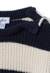 Suéter de punto a rayas en azul marino y crema, con hilo texturizado, que presenta un cuello de canalé y dos botones negros en el hombro para el cierre.