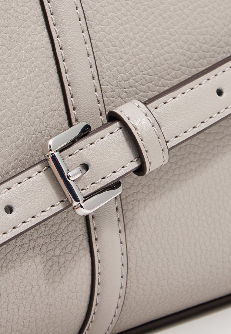 Sac en cuir gris clair avec une surface texturée, accentué par une boucle en argent brillant et des détails de couture. Bandoulière plate avec une finition lisse.