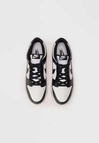 Melnas un baltas Nike kedas ar perforētu baltas ādas purngalu, melnām ādas akcentiem un platu melnu šņorējumu.