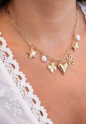 Collar de tono dorado con cadena enlazada que presenta encantos en forma de estrella, corazón, flor y perla, mostrando diversas formas y texturas.
