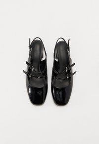 Chaussures slingback en cuir verni noir avec un bout carré, dotées de trois brides ajustables et d'un petit talon. Texture lisse avec finition brillante.