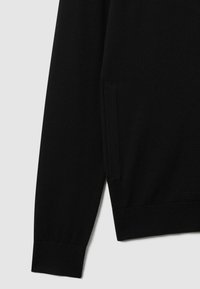 Maglione nero lavorato a maglia con maniche lunghe, polsini e orlo a coste, e una tasca laterale. Texture liscia con una silhouette fitted.