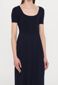 Marineblaues, geripptes Kleid mit rundem Ausschnitt, kurzen Ärmeln und einem plissierten Rock, durchgehend mit einer glatten Textur.